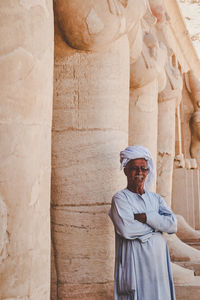 Portrait of man in traditional clothing standing against columns