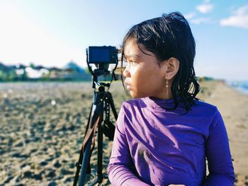 Midsection of woman photographing bicycle on beach