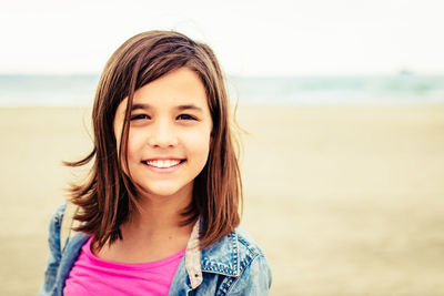 Portrait of smiling girl standing at beach against sky