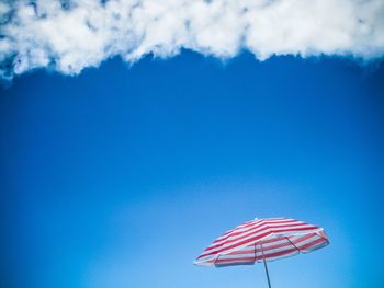 Low angle view of umbrella against blue sky