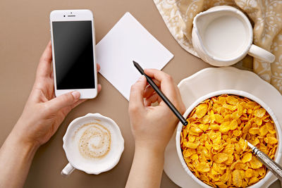 Directly above shot of woman holding coffee cup on table