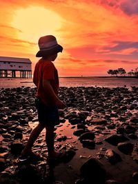 Silhouette person on beach against sky during sunset