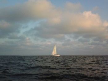 Boats in sea against cloudy sky