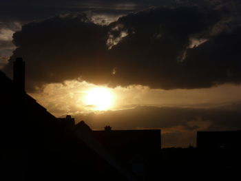 Silhouette of buildings against cloudy sky at sunset