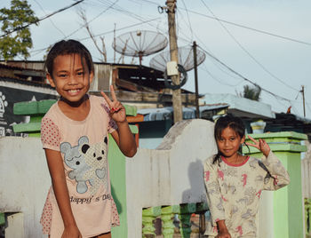 Portrait of smiling mother and daughter standing against sky