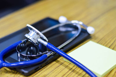 High angle view of digital tablet with stethoscope and adhesive note on wooden table