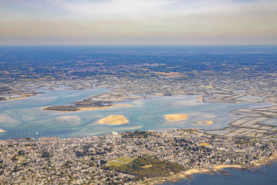 Aerial view of city by sea against sky