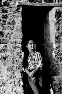 Portrait of smiling young woman standing on doorway 