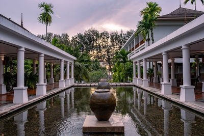 Fountain by lake and building against sky