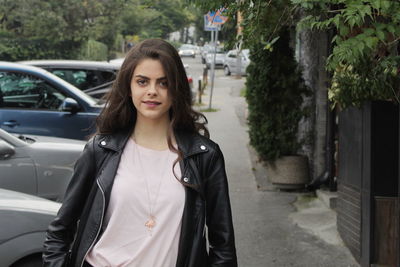 Portrait of young woman standing in car