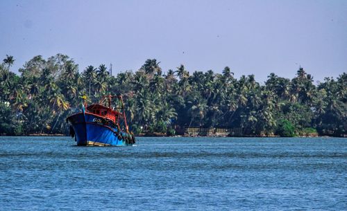 Boat sailing in river against clear sky