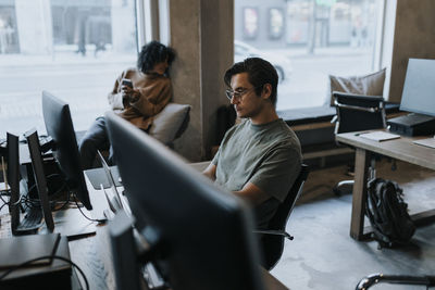 Young businessman working on laptop at desk in creative office