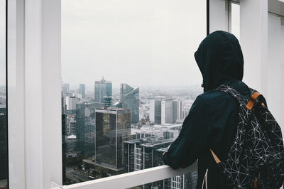 Rear view of man and woman standing against window in city