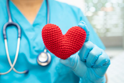 Midsection of doctor holding heart shape