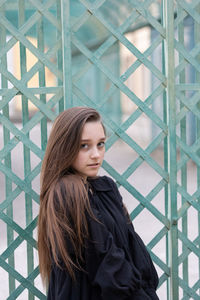 Portrait of beautiful young woman standing against black background