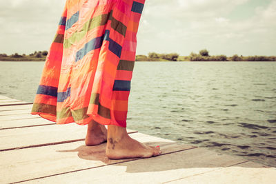 Low section of woman standing on pier during sunny day