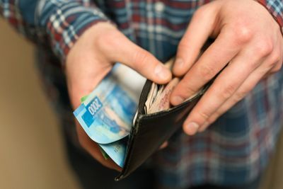 Midsection of man removing paper currency from wallet