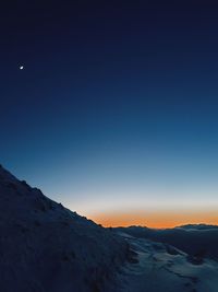 Scenic view of snowcapped mountains against clear blue sky at night