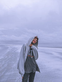 Man standing in sea against sky during winter