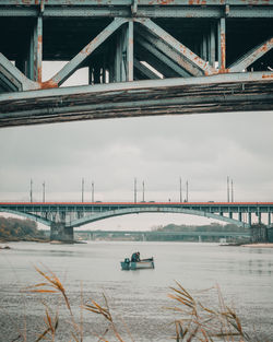 Bridge over river in city against sky