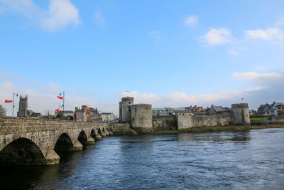 Arch bridge over river against buildings