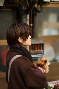 Side view of woman holding dog standing outdoors