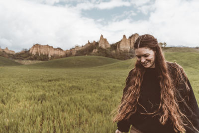 Young woman standing on field against sky