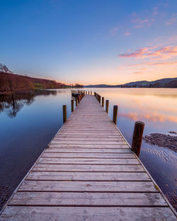 Wooden pier over lake against sky during sunset