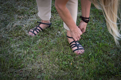 Low section of woman wearing sandal on grass