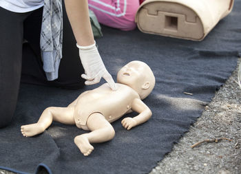 Midsection of paramedics performing cpr on baby mannequin