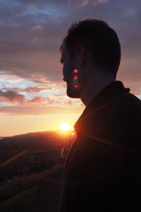 Young man standing against sky during sunset