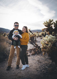 A family is standing near a cactus in the desert, california