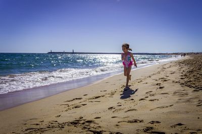 Full length of woman on beach against clear sky