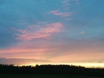 Silhouette trees on field against sky at sunset