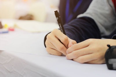 Cropped hand of woman writing in paper