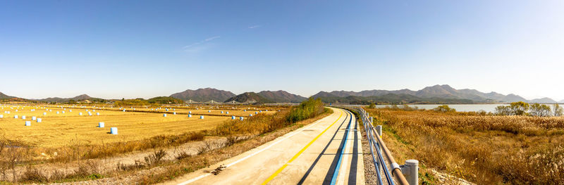 Panoramic shot of empty road on field against clear sky