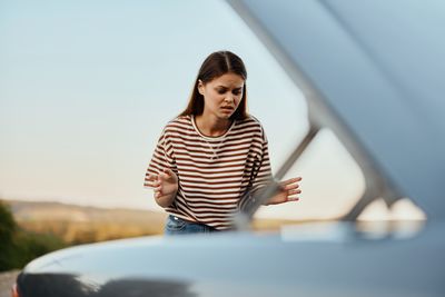 Portrait of young woman sitting on car