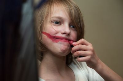 Portrait of a kid painting red smile on his face