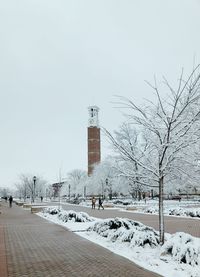 Bare trees on snow covered building against sky