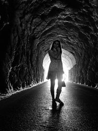 Full length of young woman standing on road in tunnel