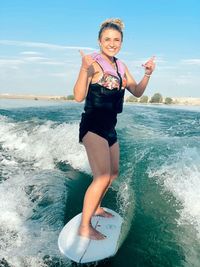 Portrait of young woman surfboarding in sea