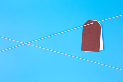Papers hanging on rope against blue background