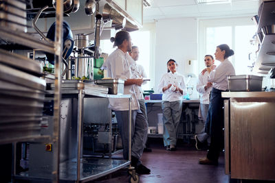 Male and female chefs having discussion in commercial kitchen
