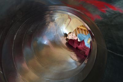 Portrait of cute girl gesturing peace sign in tunnel slide