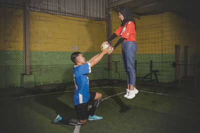 Full length of woman levitating in air while holding ball