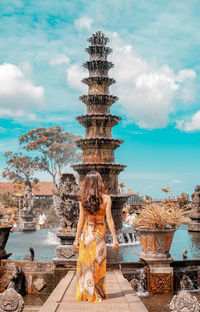 Rear view of woman looking at fountain while standing on footpath