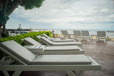 Chairs and table by sea against sky