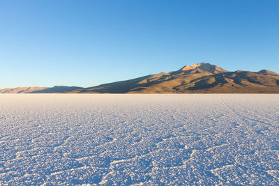 Scenic view of arid landscape against clear blue sky