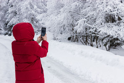 Man photographing bare trees during winter