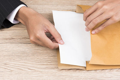 Cropped hands of businesswoman putting paper in envelope at office